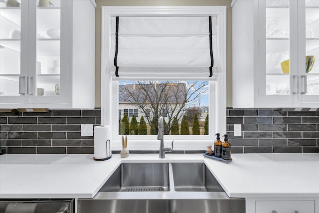 details with dishwasher, light countertops, white cabinets, and glass insert cabinets