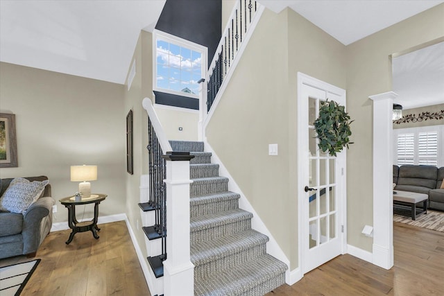 stairway with baseboards, a high ceiling, and wood finished floors