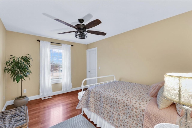 bedroom featuring a ceiling fan, visible vents, wood finished floors, and baseboards