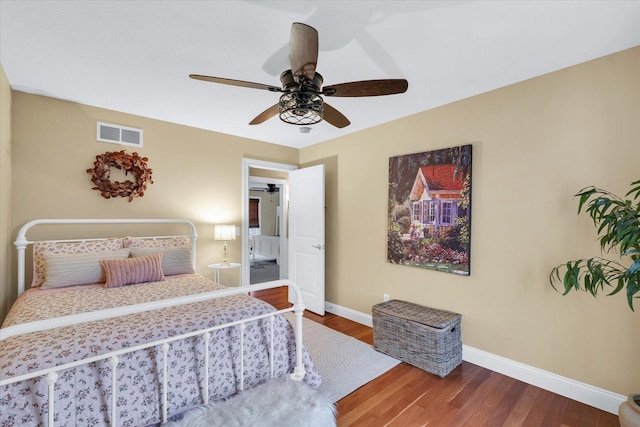 bedroom with wood finished floors, visible vents, and baseboards