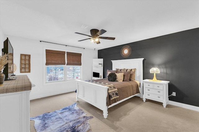 bedroom with light carpet, ceiling fan, and baseboards