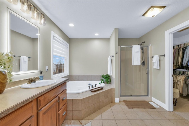 bathroom with vanity, a shower stall, a walk in closet, a garden tub, and tile patterned floors