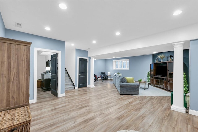 living room featuring light wood-type flooring, visible vents, recessed lighting, stairs, and ornate columns