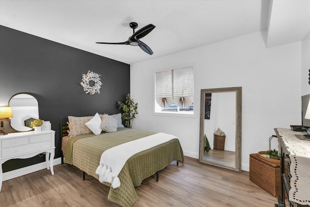 bedroom with ceiling fan, baseboards, and light wood-style flooring