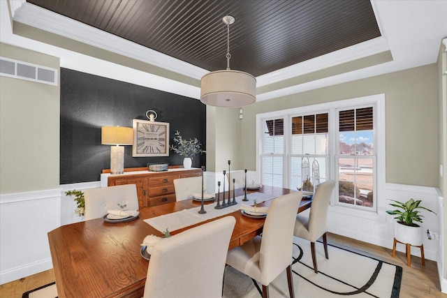 dining area with a raised ceiling, visible vents, wooden ceiling, and wainscoting