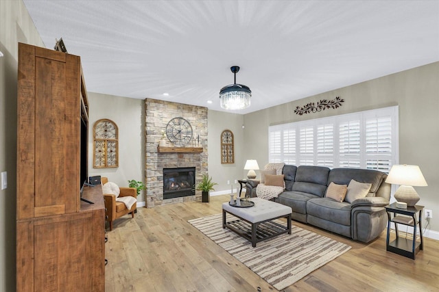 living area featuring a stone fireplace, light wood-style flooring, and baseboards