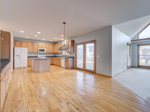 kitchen with pendant lighting, white appliances, plenty of natural light, and a kitchen island