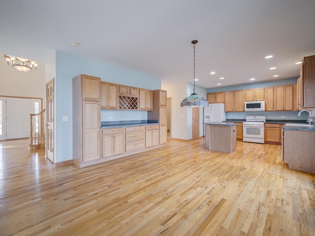 kitchen featuring an inviting chandelier, decorative light fixtures, light wood-type flooring, a kitchen island, and white appliances