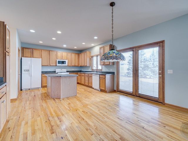 kitchen featuring white appliances, decorative light fixtures, a center island, and light wood-type flooring