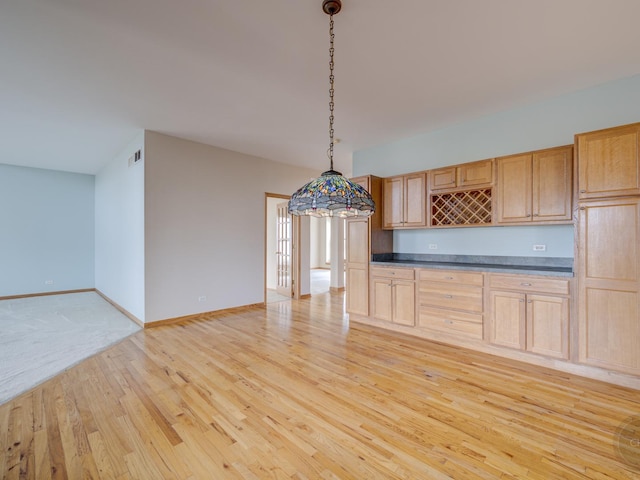 kitchen featuring decorative light fixtures, light brown cabinetry, and light wood-type flooring