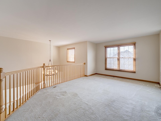 carpeted spare room featuring an inviting chandelier