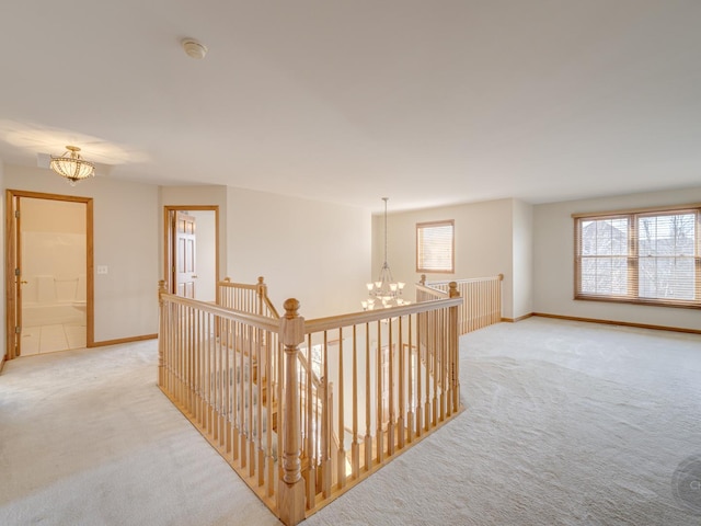 hall featuring a wealth of natural light, light carpet, and a notable chandelier