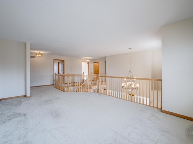 carpeted empty room featuring a notable chandelier