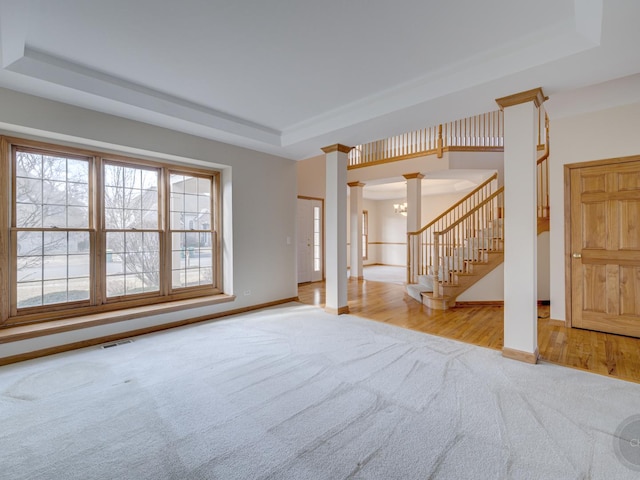 unfurnished living room with light carpet, a notable chandelier, and a tray ceiling