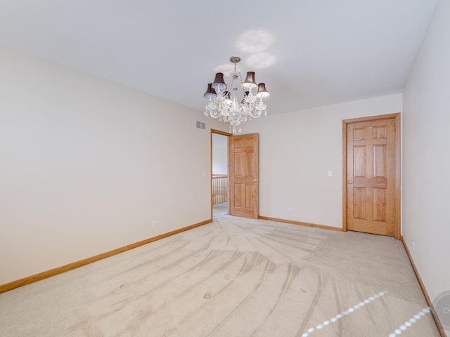 carpeted spare room featuring an inviting chandelier