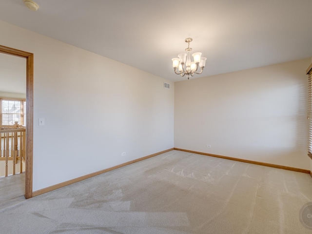 carpeted empty room featuring a notable chandelier