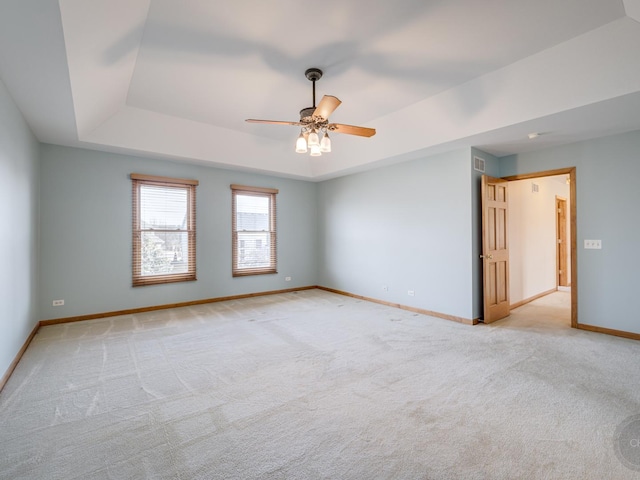 carpeted empty room featuring a raised ceiling and ceiling fan