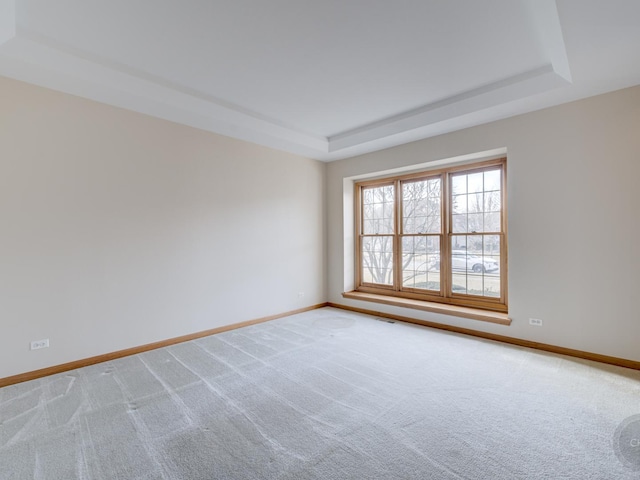 carpeted empty room featuring a raised ceiling