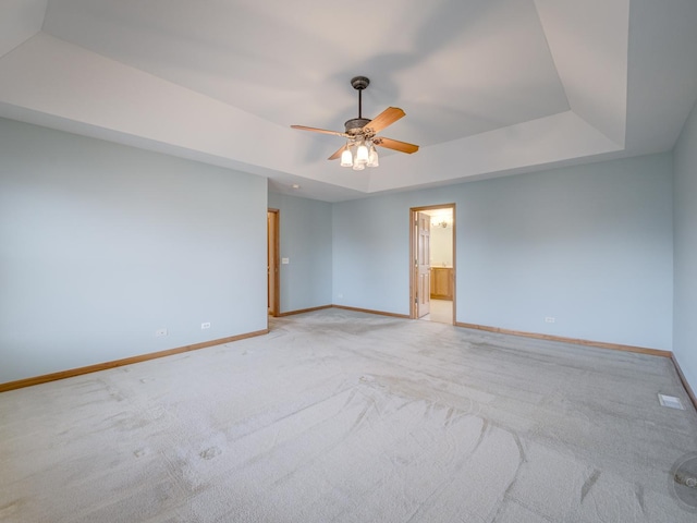 carpeted empty room featuring ceiling fan and a raised ceiling