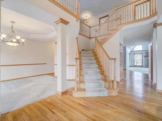 stairs featuring an inviting chandelier, hardwood / wood-style floors, a towering ceiling, and a tray ceiling