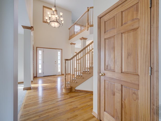 foyer entrance featuring a notable chandelier, a high ceiling, and light wood-type flooring