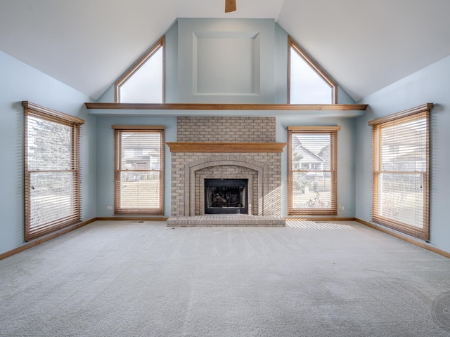 unfurnished living room featuring a wealth of natural light, a brick fireplace, light colored carpet, and high vaulted ceiling