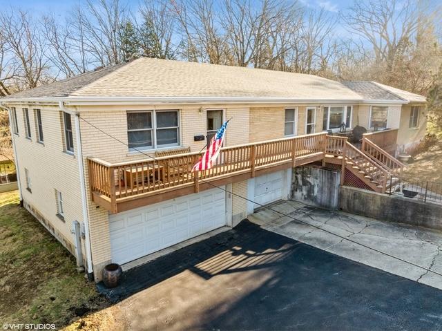 single story home featuring driveway, an attached garage, a shingled roof, brick siding, and stairs