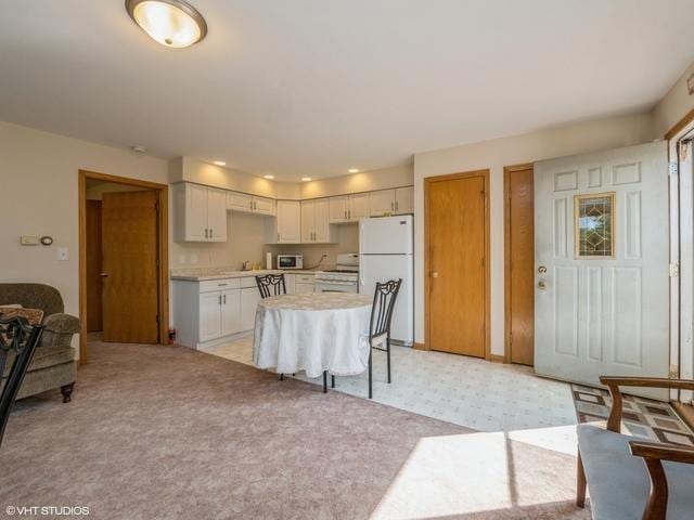 kitchen with a kitchen island, light floors, light countertops, light carpet, and white appliances