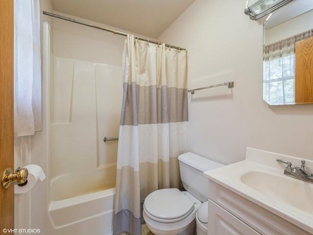 full bathroom with shower / bathtub combination with curtain, toilet, and vanity