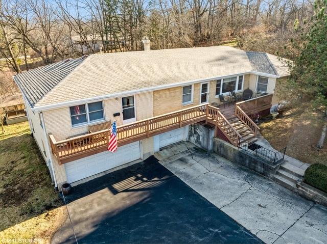 view of front facade with stairs, a garage, driveway, and a chimney