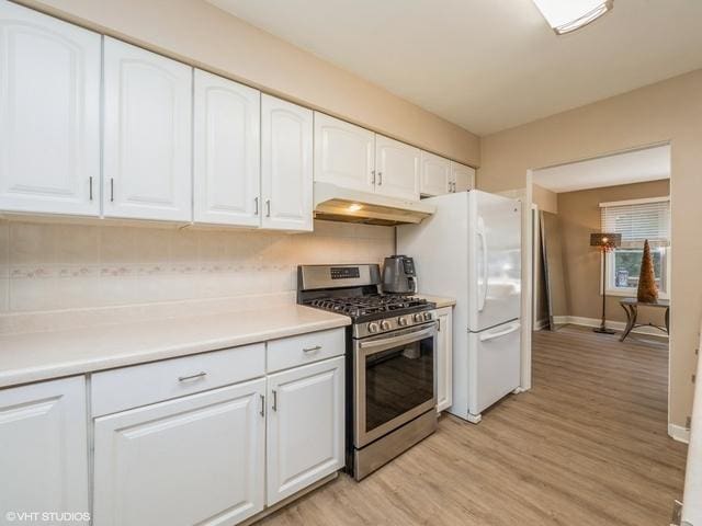 kitchen with stainless steel gas stove, under cabinet range hood, backsplash, white cabinets, and light wood finished floors