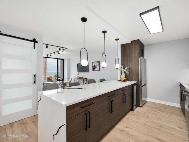 kitchen with dark brown cabinets, stainless steel fridge, light hardwood / wood-style floors, and decorative light fixtures