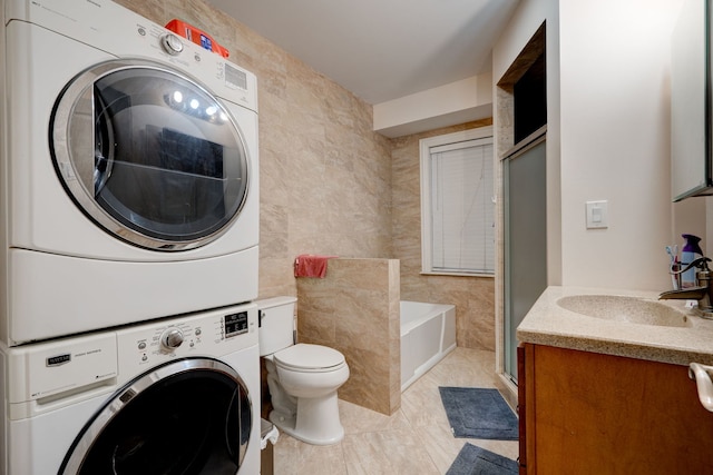 4820 W George St, Chicago, IL 60641 - full bathroom featuring a stall shower, toilet, stacked washer and clothes dryer, a bath, and tile walls