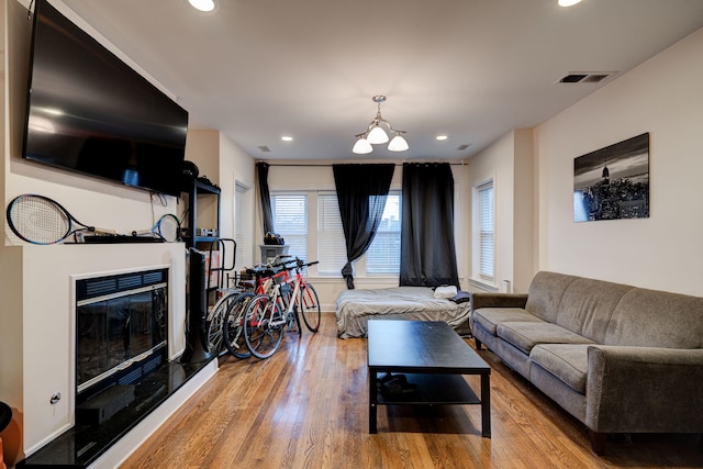 4820 W George St, Chicago, IL 60641 - living area with wood finished floors, a glass covered fireplace, visible vents, recessed lighting, and an inviting chandelier