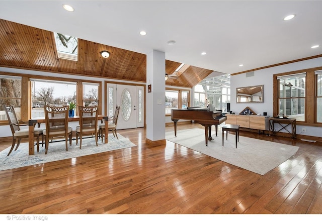 entrance foyer featuring wood ceiling, ceiling fan, hardwood / wood-style floors, lofted ceiling with skylight, and ornamental molding