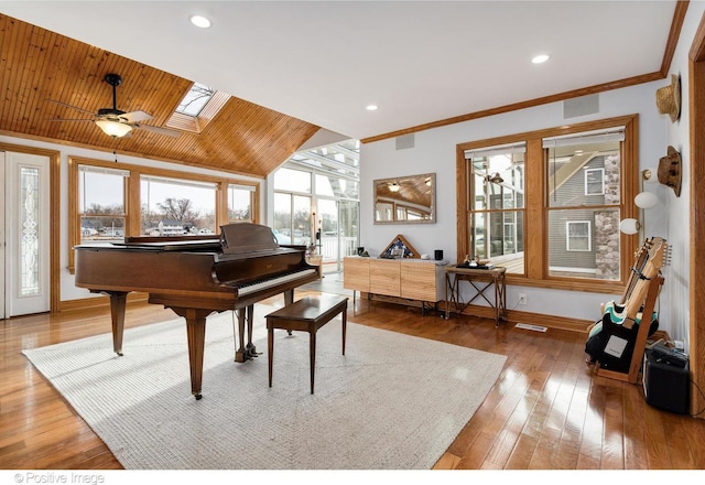 living area with hardwood / wood-style flooring, crown molding, and lofted ceiling with skylight