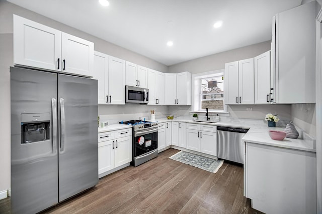 kitchen with appliances with stainless steel finishes, dark hardwood / wood-style floors, sink, white cabinets, and light stone counters