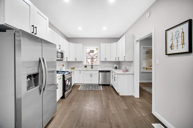 kitchen featuring sink, hardwood / wood-style flooring, stainless steel appliances, and white cabinets