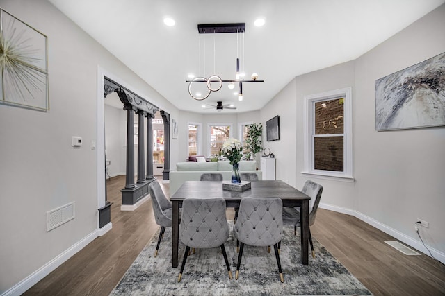 dining space featuring an inviting chandelier, dark hardwood / wood-style flooring, and decorative columns