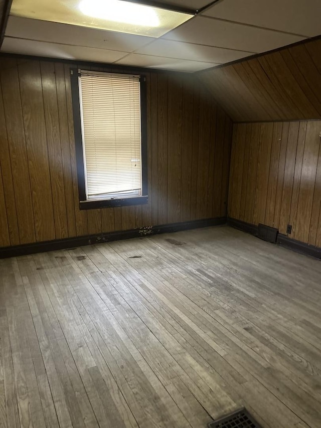 bonus room featuring lofted ceiling, light hardwood / wood-style floors, and wood walls