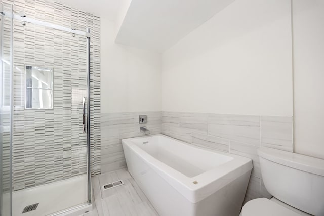 bathroom with tile walls, toilet, and separate shower and tub