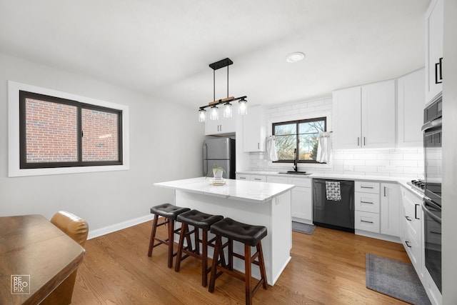 kitchen with dishwashing machine, stainless steel fridge, a kitchen breakfast bar, a center island, and white cabinets