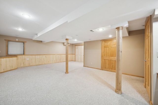 basement featuring light colored carpet and wooden walls