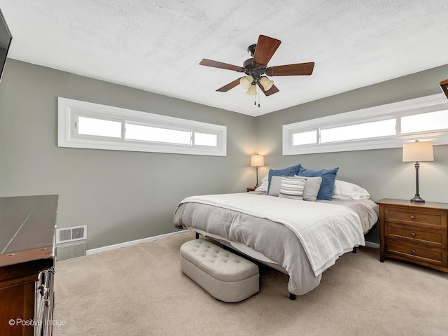 carpeted bedroom featuring multiple windows, ceiling fan, and a textured ceiling