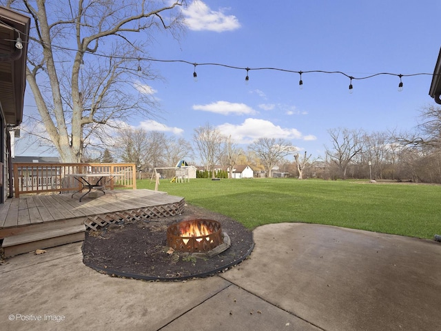 view of patio with an outdoor fire pit, a deck, and a playground