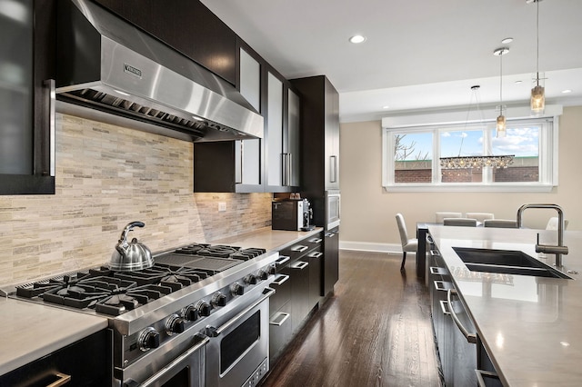 kitchen with sink, hanging light fixtures, appliances with stainless steel finishes, dark hardwood / wood-style floors, and range hood