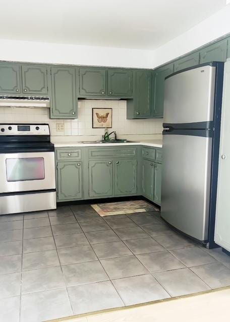 kitchen with tasteful backsplash, light tile patterned floors, exhaust hood, and appliances with stainless steel finishes