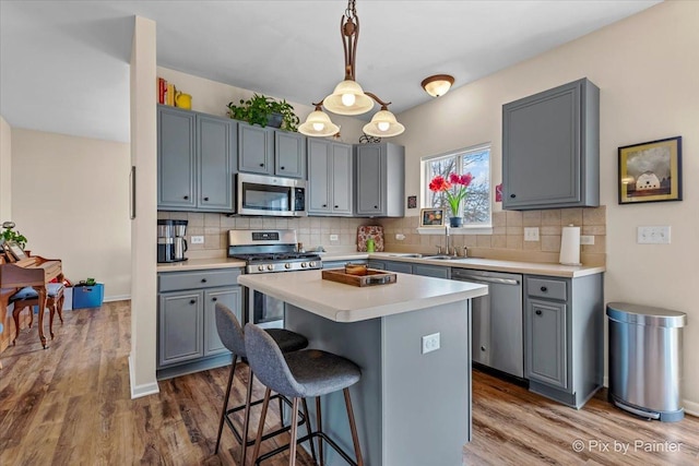 kitchen with gray cabinets, pendant lighting, sink, a center island, and stainless steel appliances