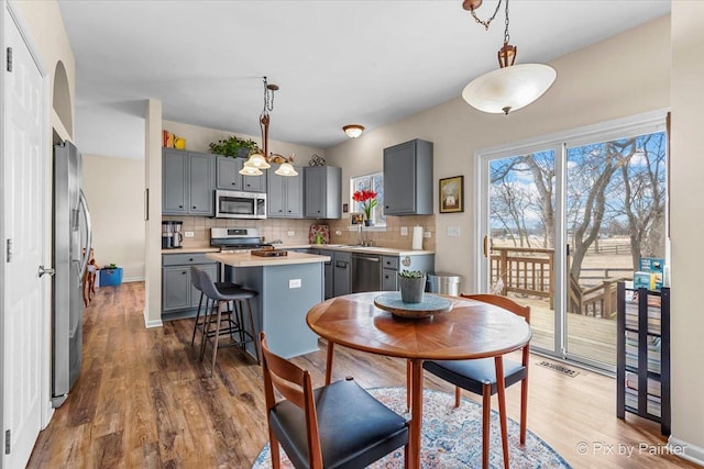 kitchen with tasteful backsplash, appliances with stainless steel finishes, a center island, and pendant lighting