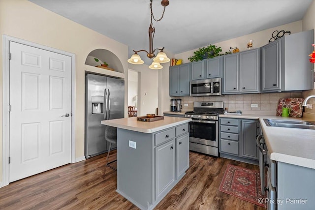 kitchen featuring pendant lighting, sink, dark wood-type flooring, stainless steel appliances, and a center island